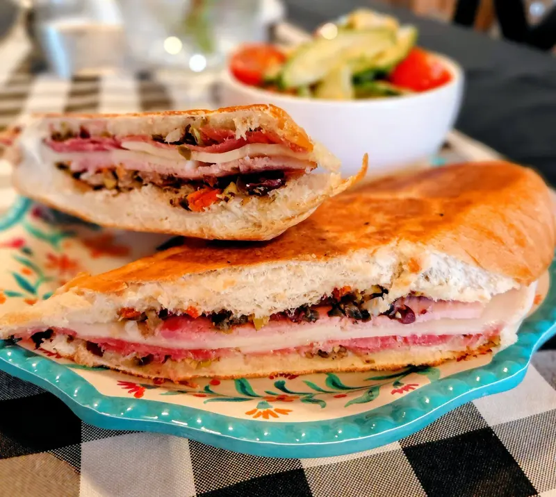 A muffuletta sandwich stacked with ham, salami, provolone and olive salad, sliced in half